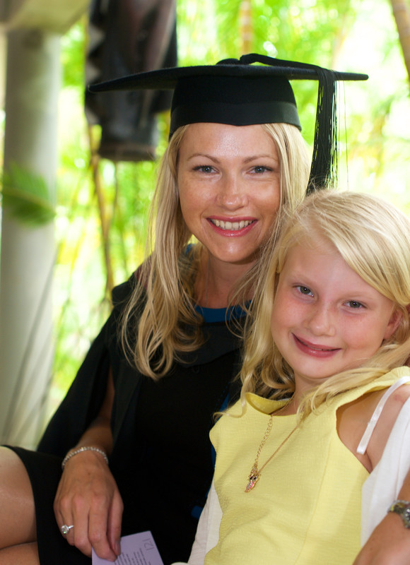 Photo of a woman wearing graduation dress sitting with her daughter